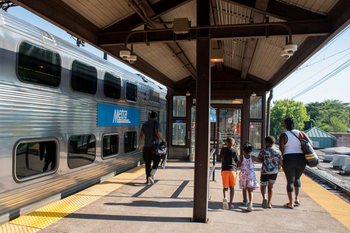A family walking on a Metra train platform, about to board the train.