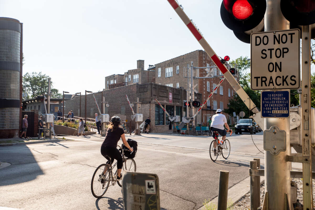 Two bikers passing a railroad crossing.