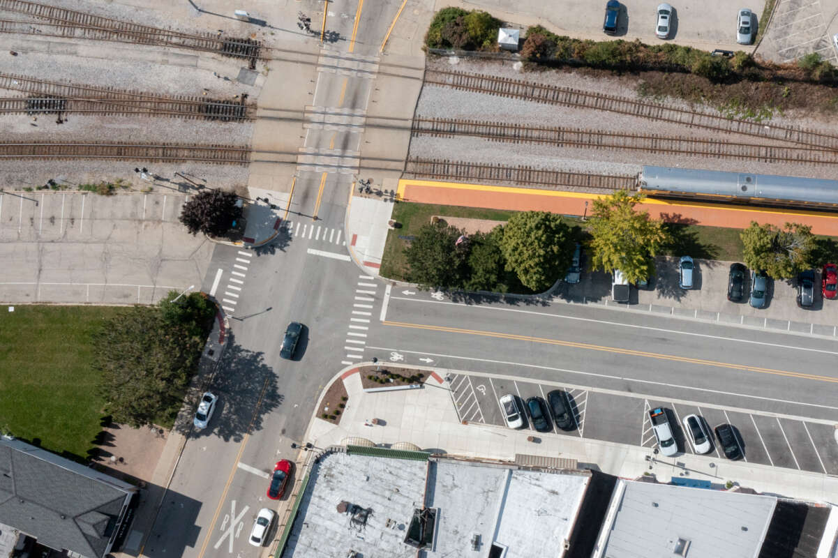 An aerial shot of train tracks, streets intersecting, and on-street parking that is about half full.