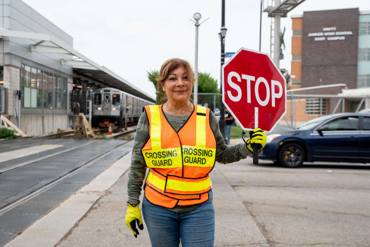 Women with crossing guard vest holding up a stop sign.
