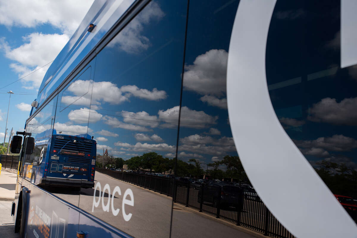 Pace bus window reflecting off a sunny blue sky and clouds.