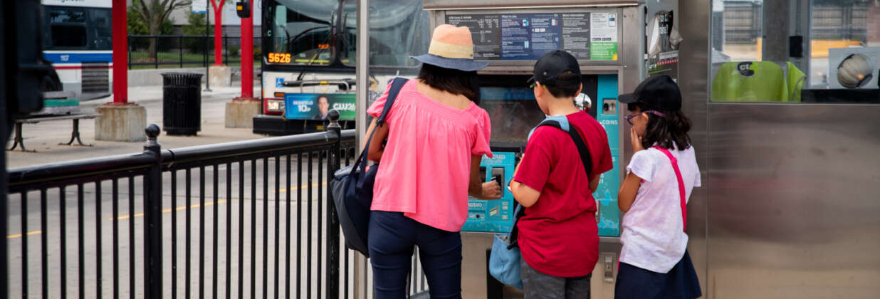 A mother with two children buying bus tickets at Ventra pay machine.