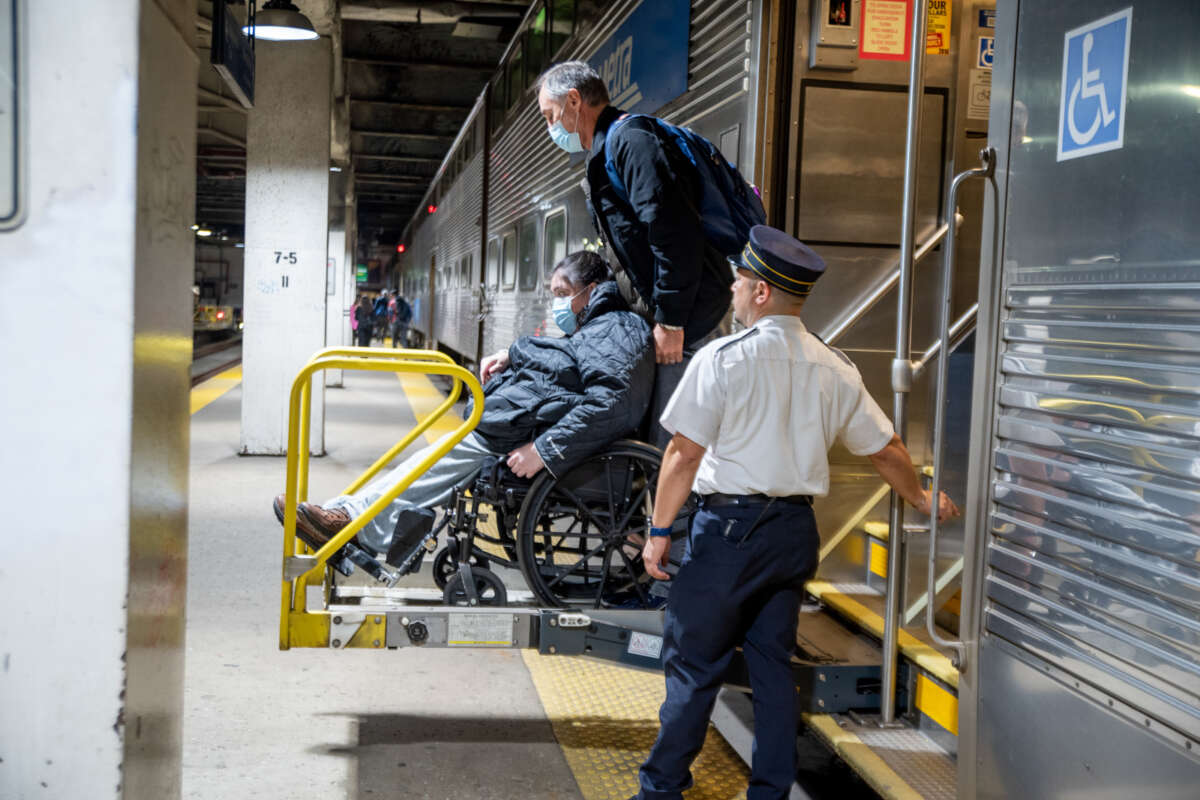 Person on wheelchair being assisted on a handicap lift to exit Metra train.