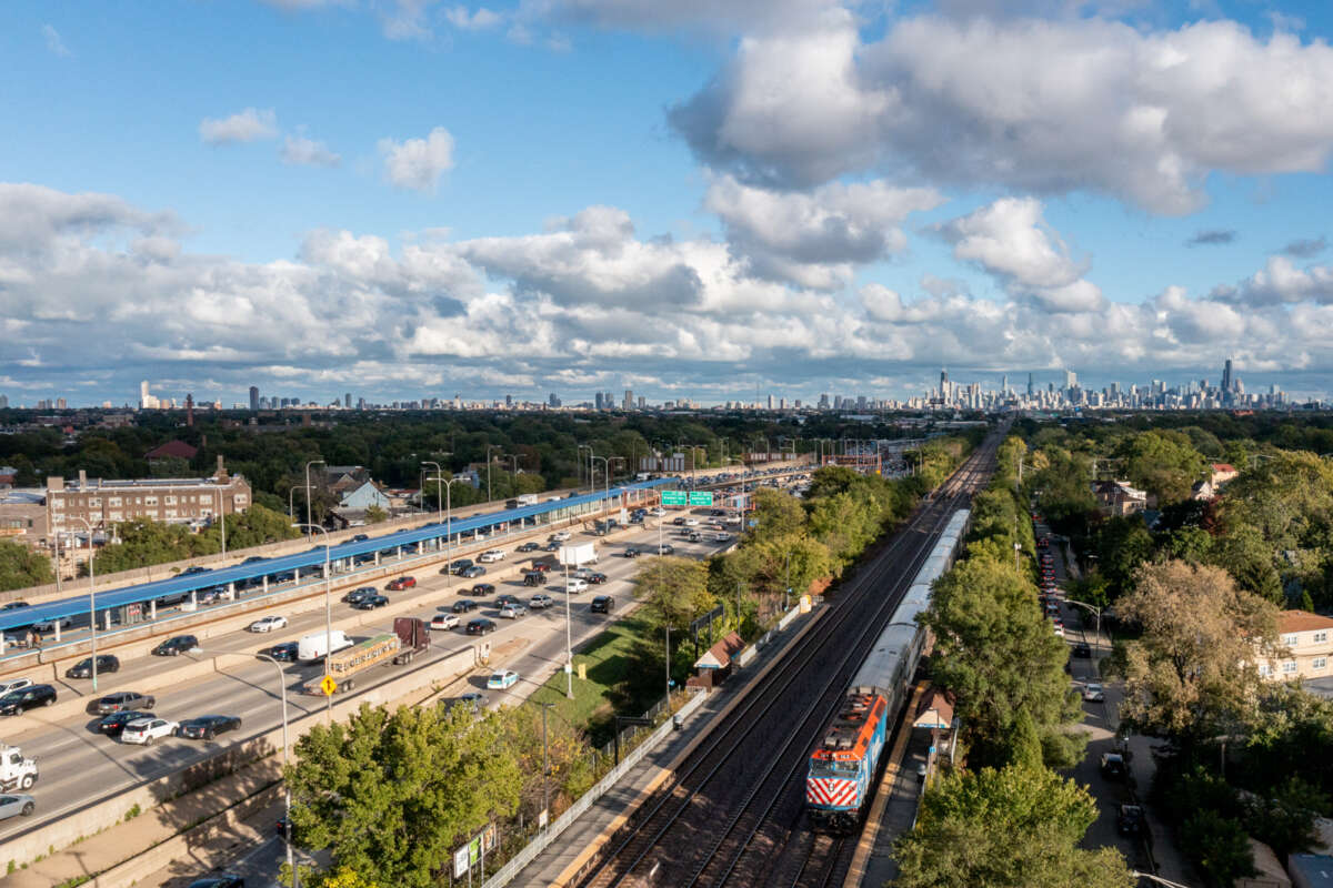 Far bird's eye-view of Chicago highway, skyline, L train tracks, and Metra train tracks.