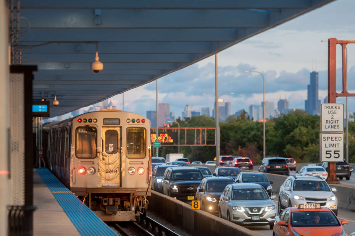 A CTA Forest Park-bound Blue Line train at a station in the middle of a congested highway.
