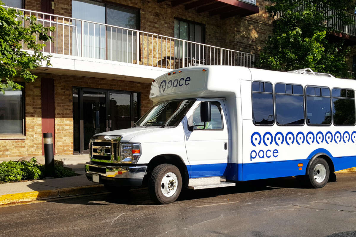 A Pace Paratransit vehicle parked outside of a multiunit residential building.