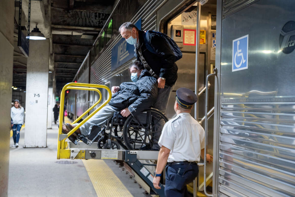Person on wheelchair getting assistance using Metra train handicap lift.