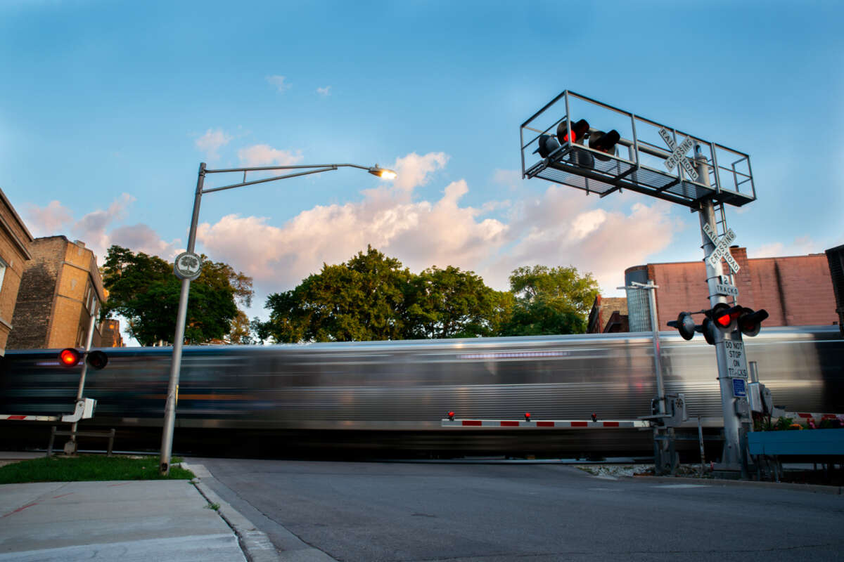 A train with motion blur at a railroad crossing.