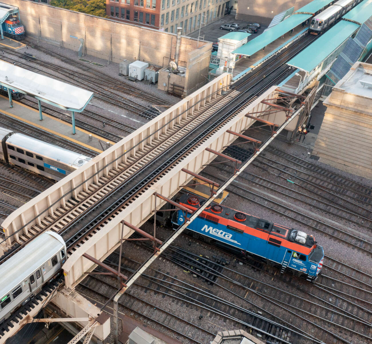 An elevated CTA train runs perpendicular to a Metra train