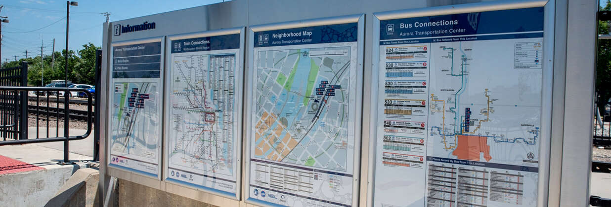 Signage at a Metra station showing train and bus connections and a neighborhood map.